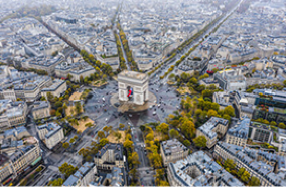 Overhead view of Paris’s Arc de Triomphe with radiating avenues and surrounding rooftops.