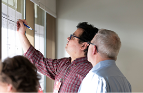 Team marking charts on wall during meeting.