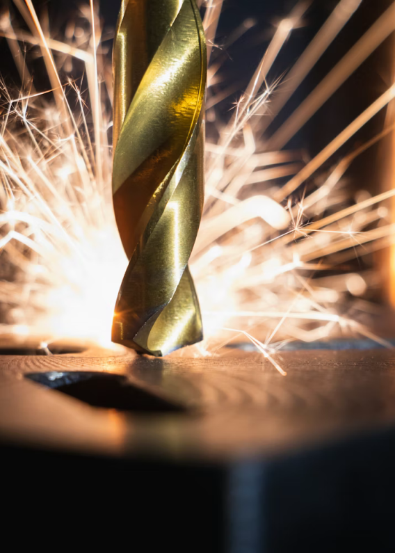 Close-up of a metal drill bit cutting into a surface with sparks flying.