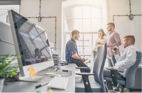 Bright workspace with desks, chairs, and team collaboration near large window.