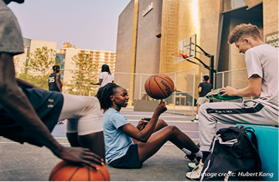 Casual moment at city basketball court with people playing and socializing at sunset.