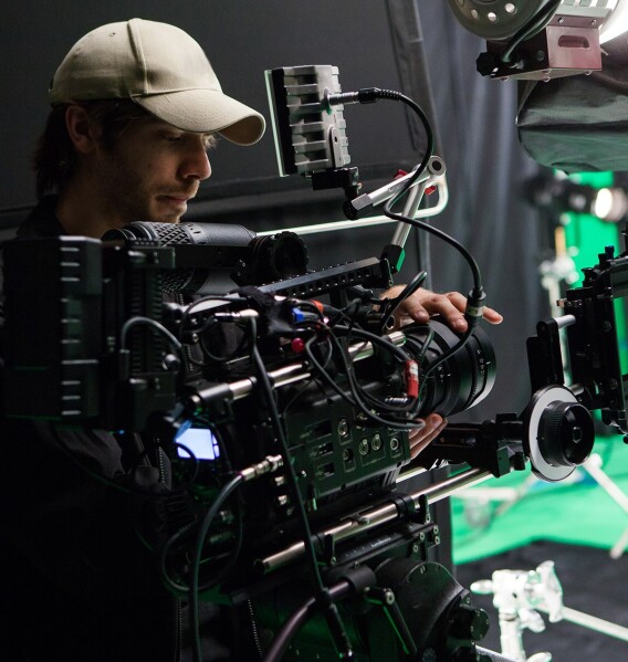 Camera operator using a digital cinema rig on an indoor production set.