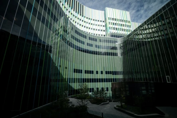 Curved glass exterior of a modern medical center surrounding a landscaped courtyard.