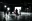 Production crew standing in silhouette around a brightly lit studio setup inside a large soundstage.